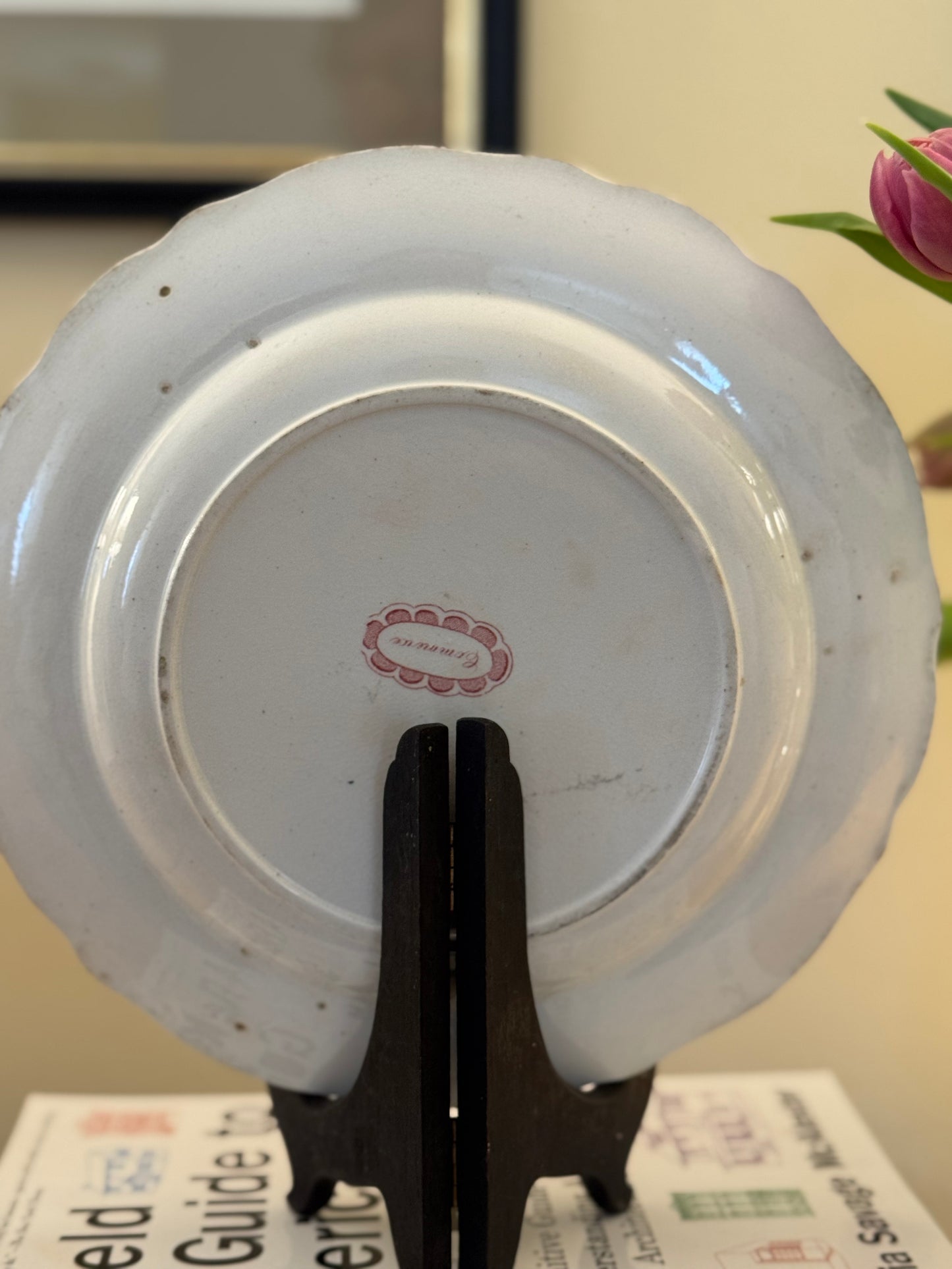 White ceramic dish with a pink label on a stand, blurred background