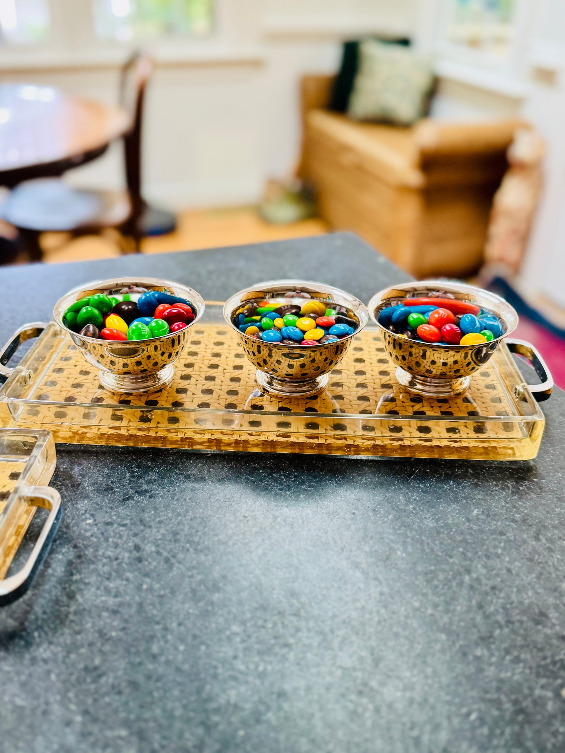 Three bowls of colorful candies on a decorative tray in a home setting.