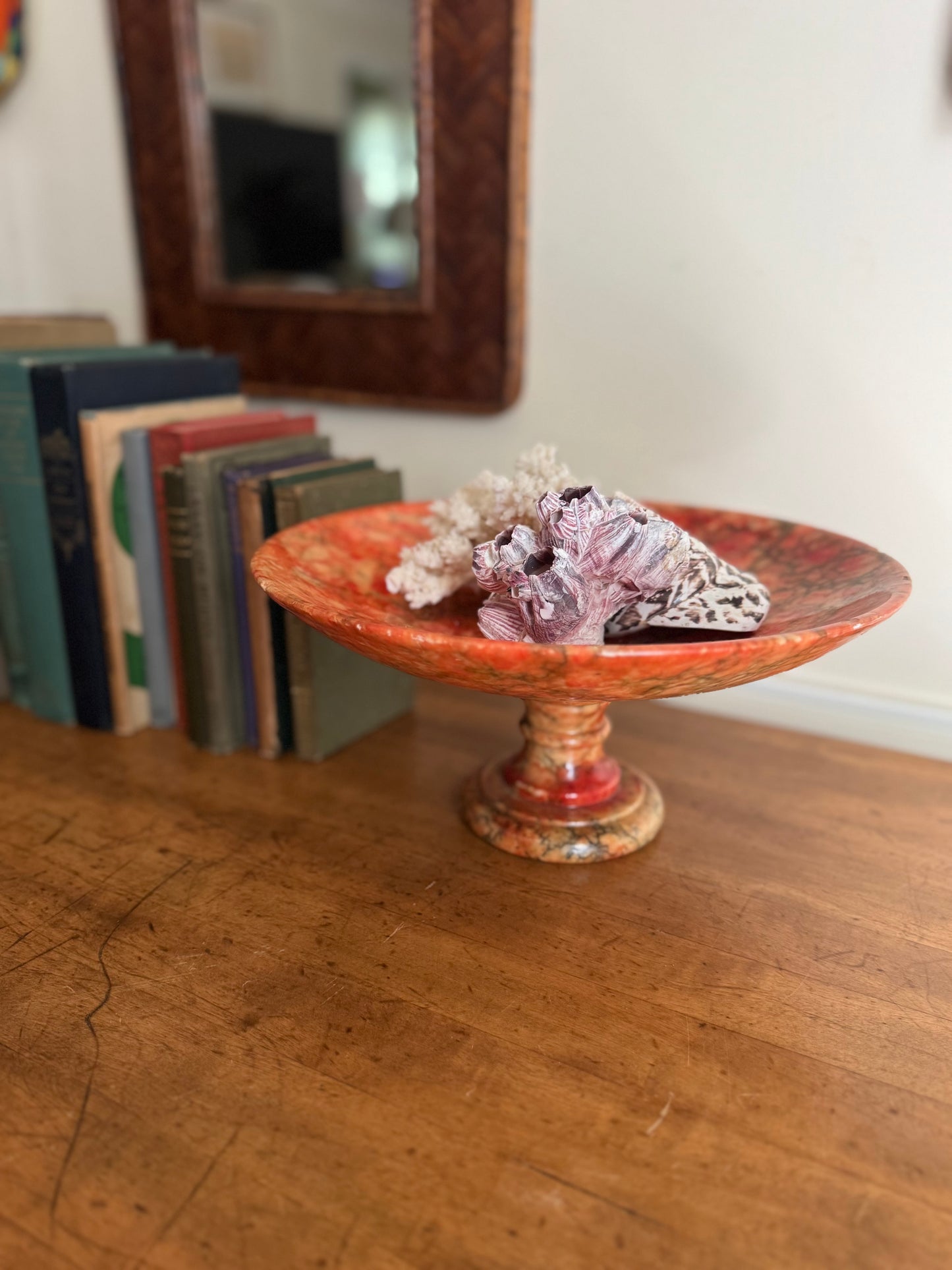 Decorative bowl with decorative stones on a wooden surface, books in the background