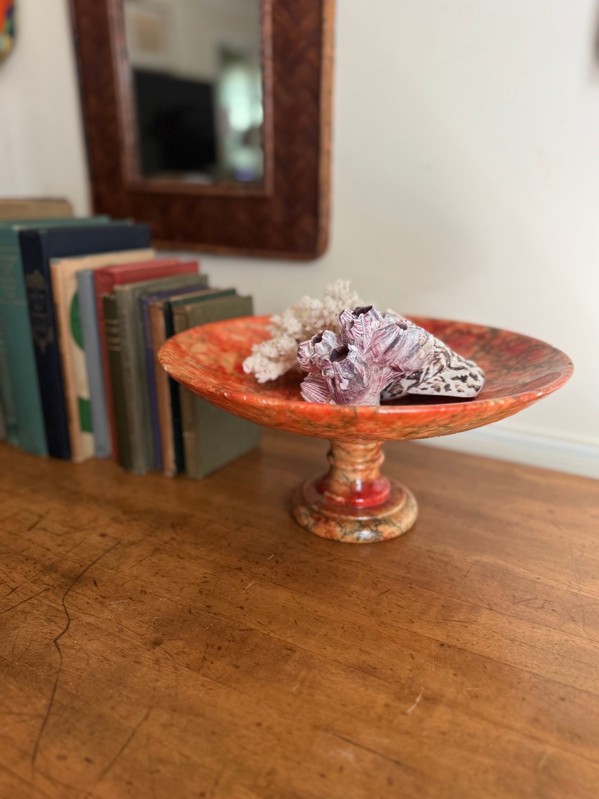 Decorative bowl with decorative stones on a wooden surface, books in the background