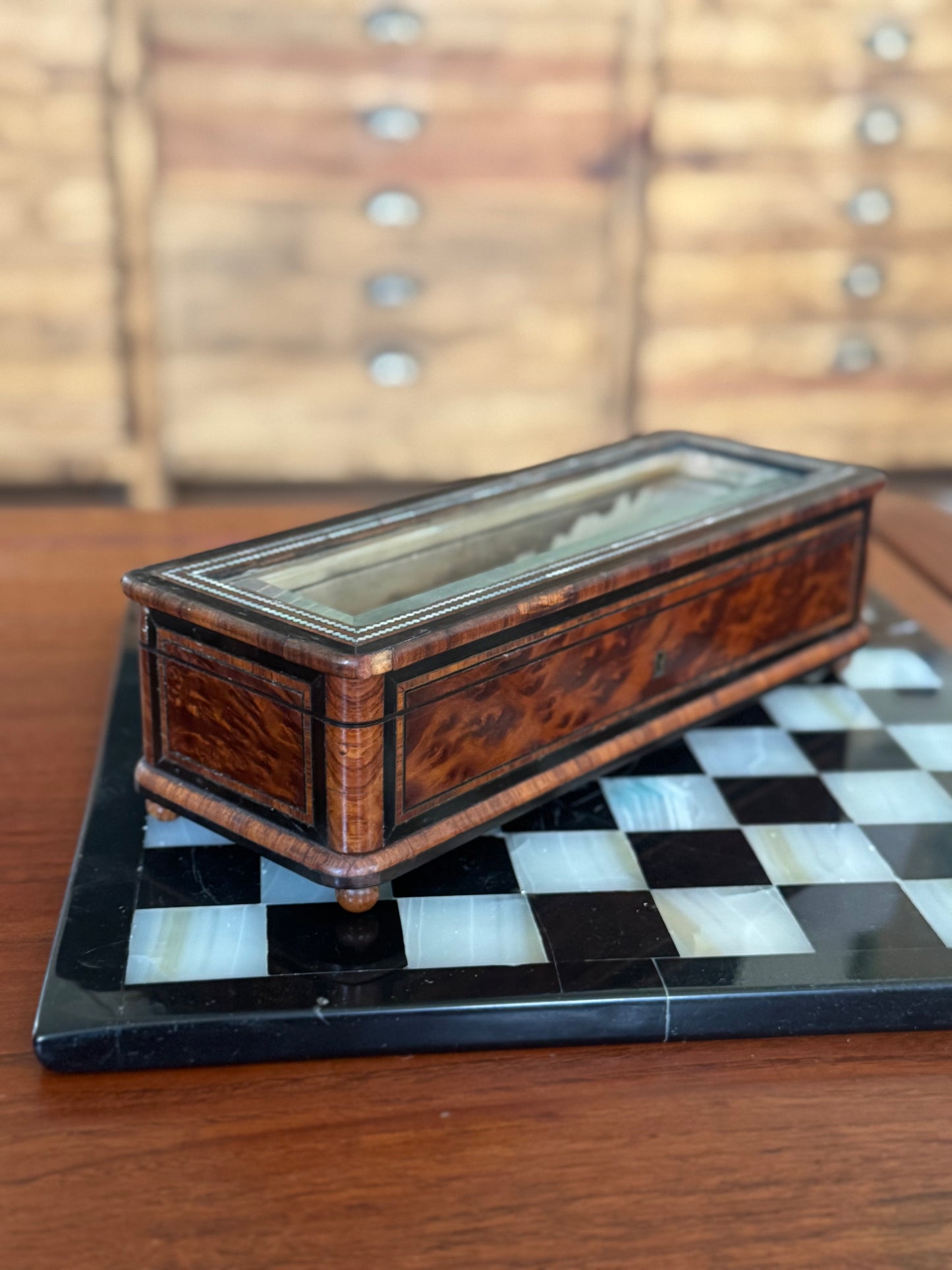 Wooden box with a glass lid on a checkered marble surface