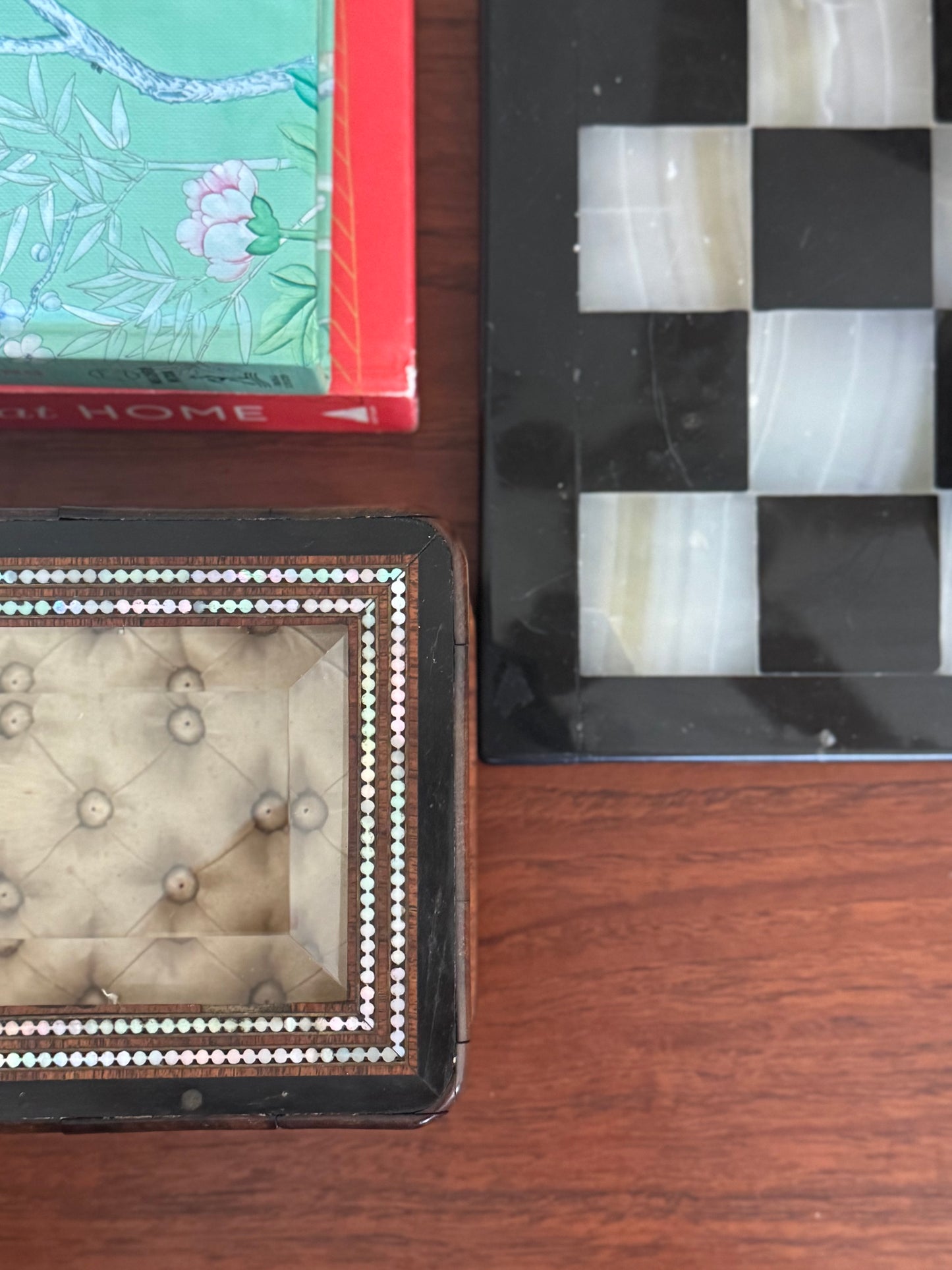 Close-up of decorative items including a checkered box, a book, and a small stone sculpture on a wooden surface.