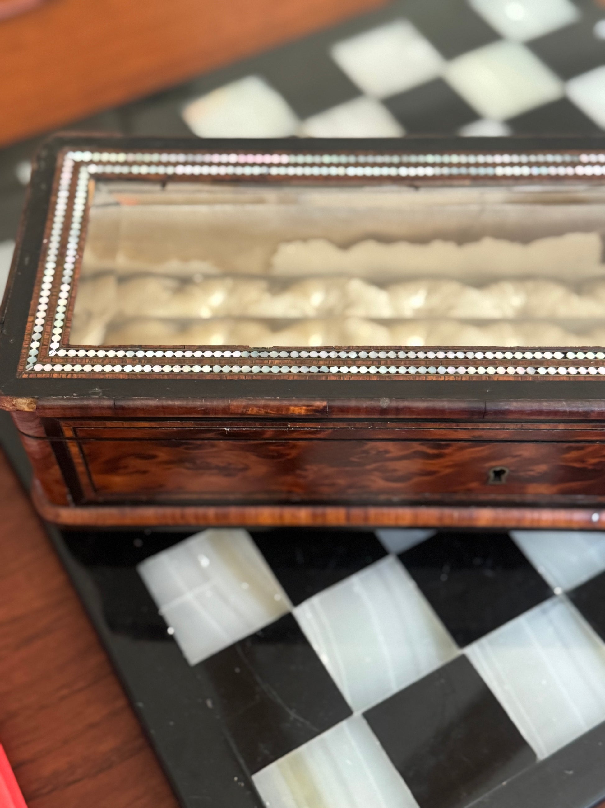 Wooden jewelry box with glass lid on a checkered surface