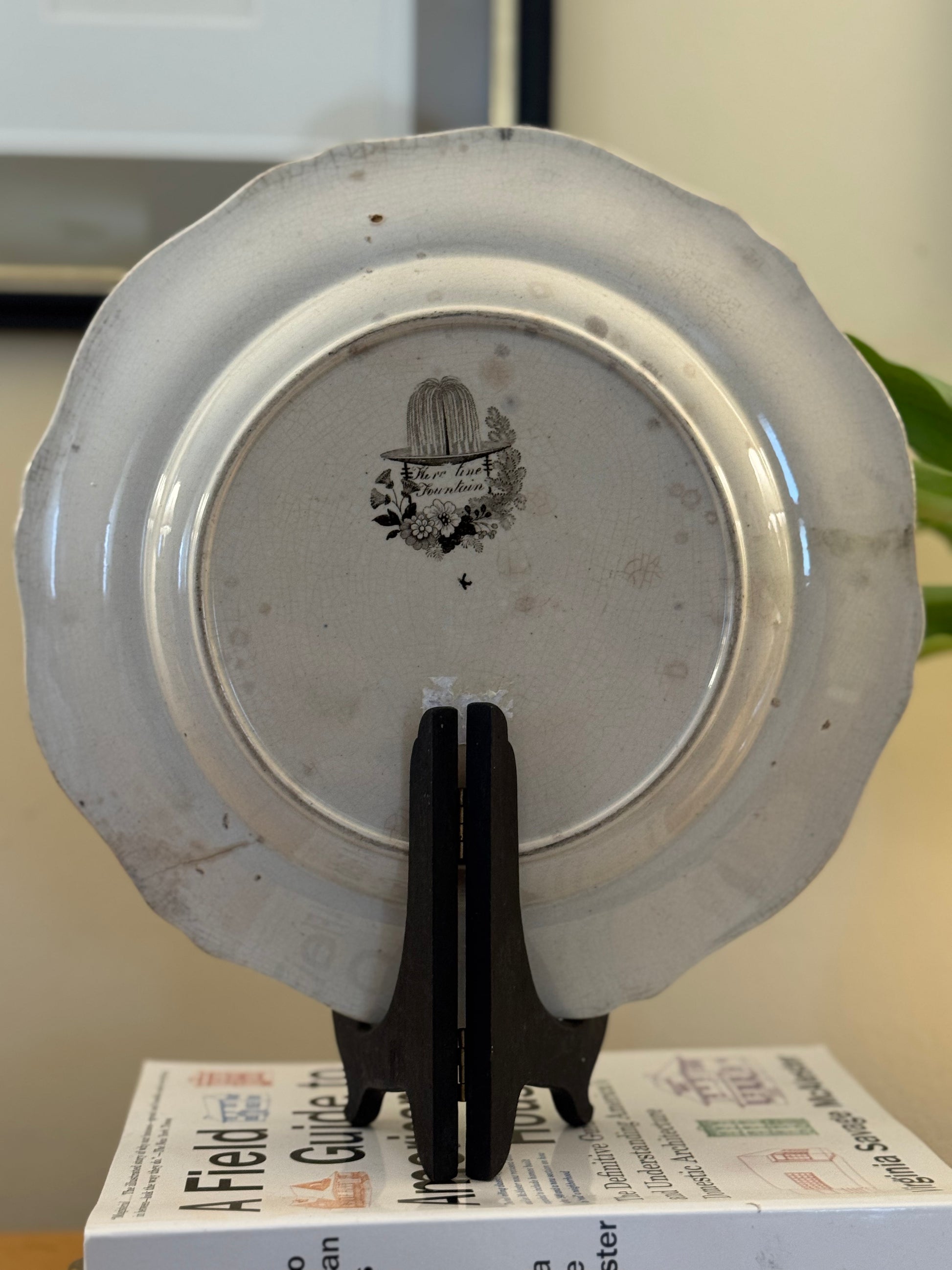 Decorative plate with a logo on a stand, placed on top of a book.